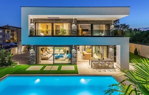 A modern two-story house with a swimming pool, featuring a glass-enclosed balcony and a stone facade. - Nice home in Medulin with sauna (Medulin)