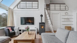 Una sala de estar moderna con chimenea, televisor y una escalera.