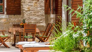 A stone building with wooden shutters, a table with chairs, and a fruit bowl. - Gorgeous home in Pula (Pula)