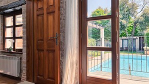 A room with a wooden door, a view of a swimming pool, and a stone wall. - Gorgeous home in Pula (Pula)