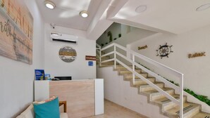 A reception area with a desk, a couch, a staircase, and a wall with decorative items. - Hotel Grand Caribe (San Andrés)