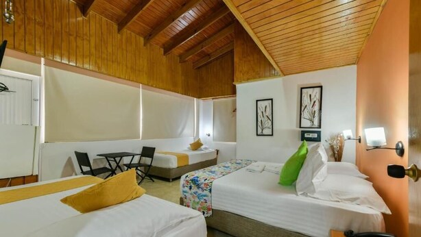A hotel room with two beds, a desk, a chair, and a small table. - Hotel Grand Caribe (San Andrés)