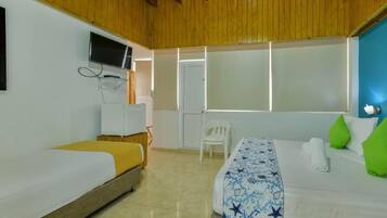 A hotel room with two beds, a television, a door, and a window.