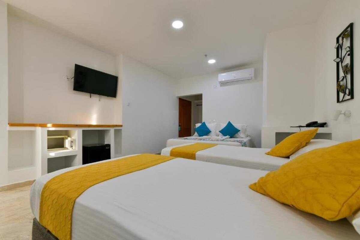 Una habitación de hotel con dos camas, televisión, escritorio y armario.