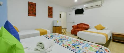 A hotel room with two beds, a TV mounted on the wall, and an air conditioning unit.