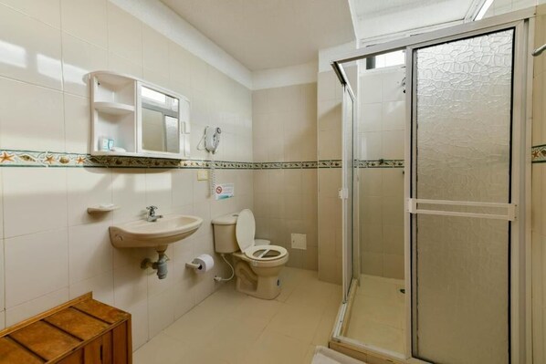 A bathroom with a sink, toilet, and glass-enclosed shower. - Hotel Grand Caribe (San Andrés)