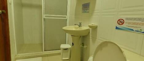 A small, basic bathroom with a toilet, sink, and shower.