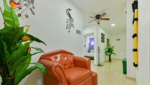 A lobby with a leather sofa, a ceiling fan, and a green plant. - Hotel Grand Caribe (San Andrés)