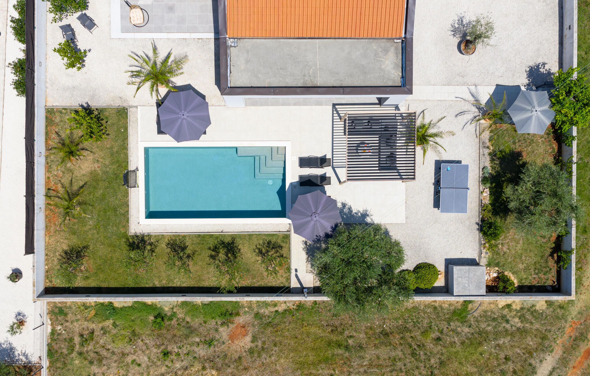 Vista aérea de uma propriedade com piscina, área de estar externa e um pátio coberto.