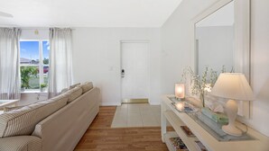 Un saló modern amb un sofà, una taula de consola amb una làmpada i un mirall gran.