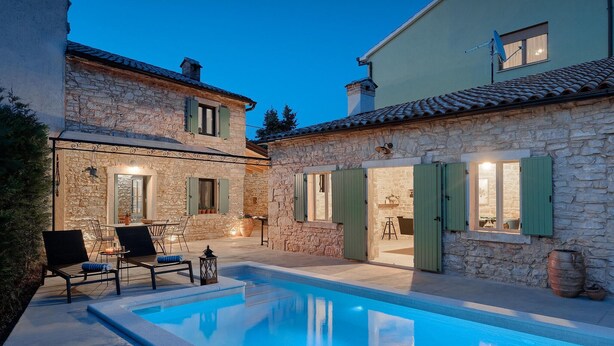 A stone house with a swimming pool, outdoor seating, and a satellite dish.
