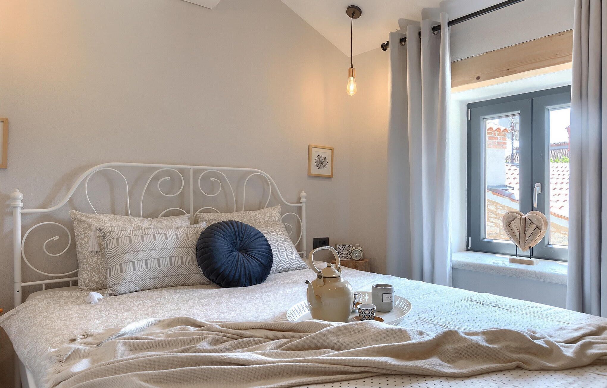 Un letto rifatto con cuscini a fantasia, un bollitore e una tazza su un comodino.