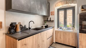 A modern kitchen with a black countertop, wooden cabinets, a built-in stove, and a window with a stone wall view.