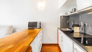 Une petite cuisine équipée d’un four à micro-ondes, d’un grille-pain, d’un évier et d’un petit plan de travail.
