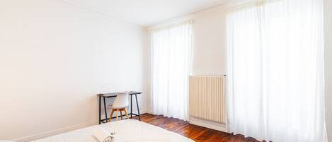 A bedroom with a bed, a desk, and a chair.