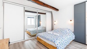 Un dormitorio con una cama de madera, un espejo grande y un armario con puerta corredera.