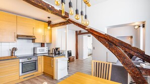 Una cocina moderna con armarios de madera, horno empotrado y comedor con mesa y sillas de madera.