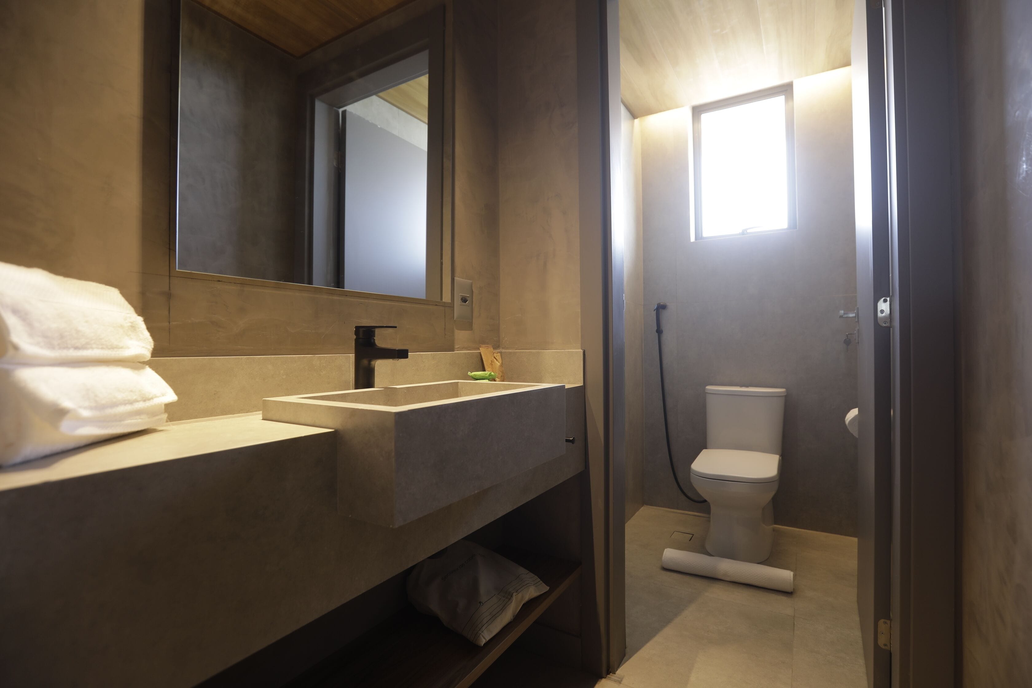 Un baño moderno con un espejo grande, un lavamanos y un inodoro.