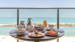 A breakfast table with various dishes and drinks, overlooking a beach and ocean. - Ritz Barra de São Miguel (Barra de São Miguel)