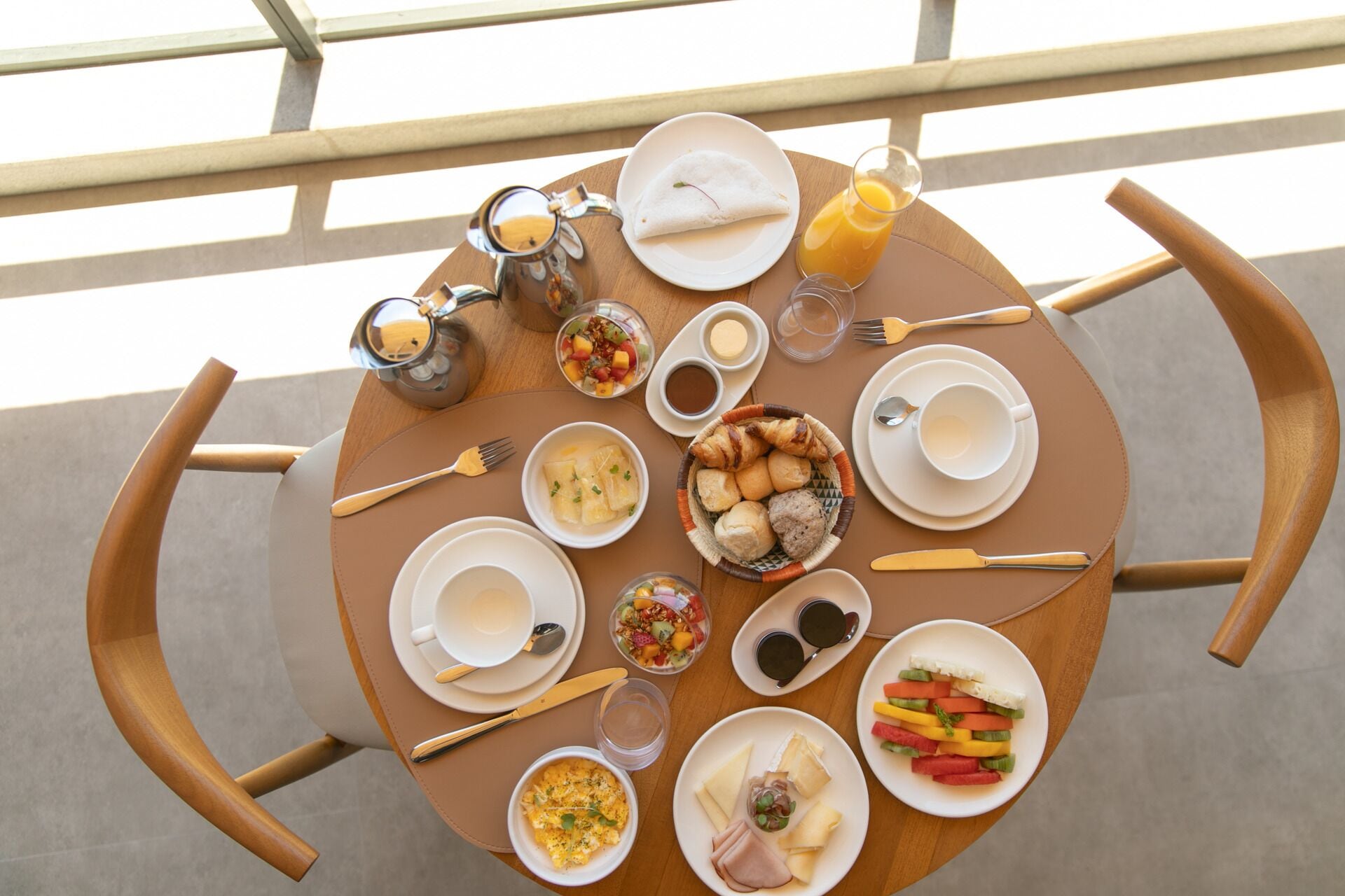 A round dining table with various breakfast items including eggs, pastries, and fruit.