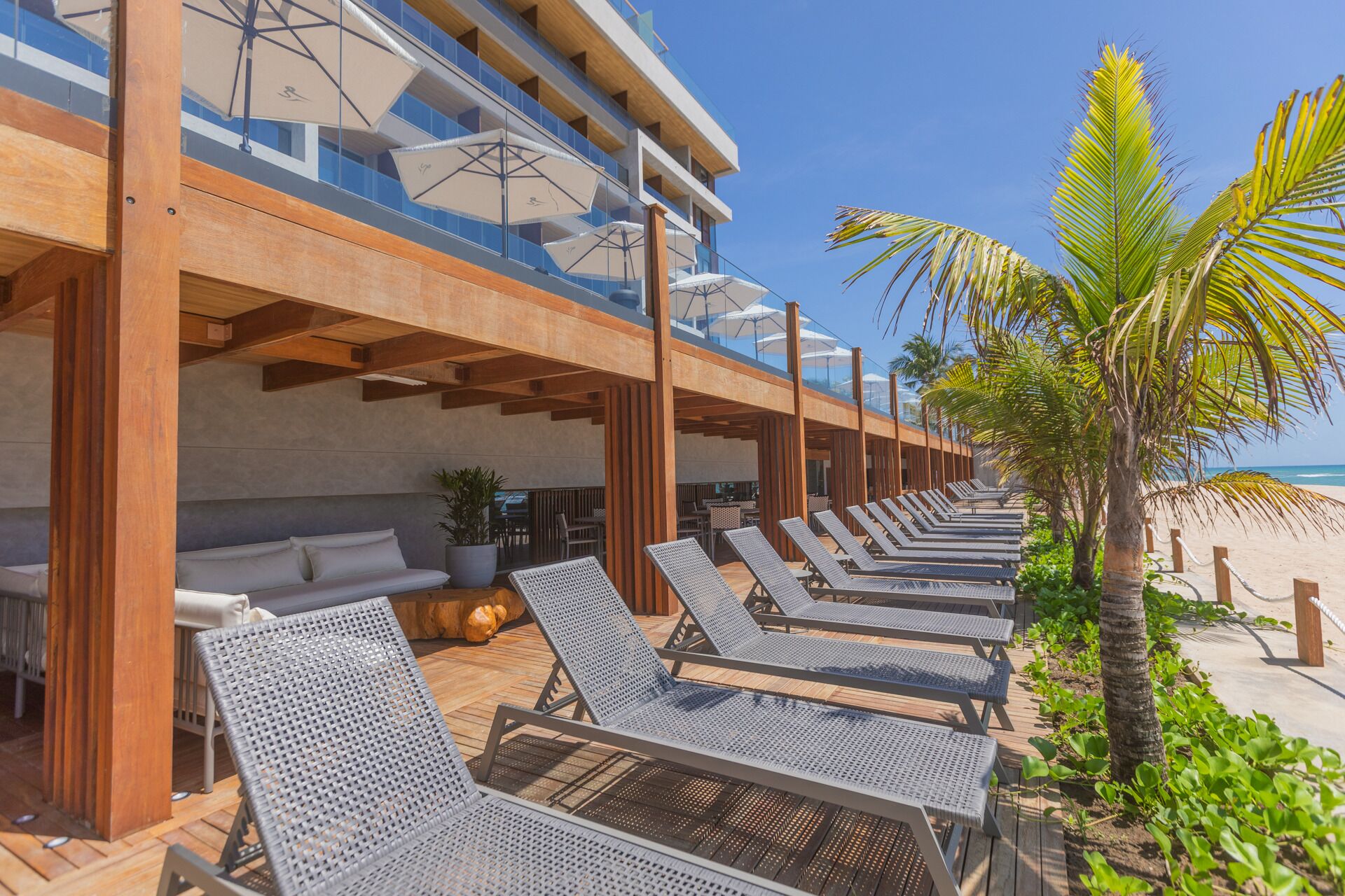 A beachside hotel with outdoor seating and lounge chairs.