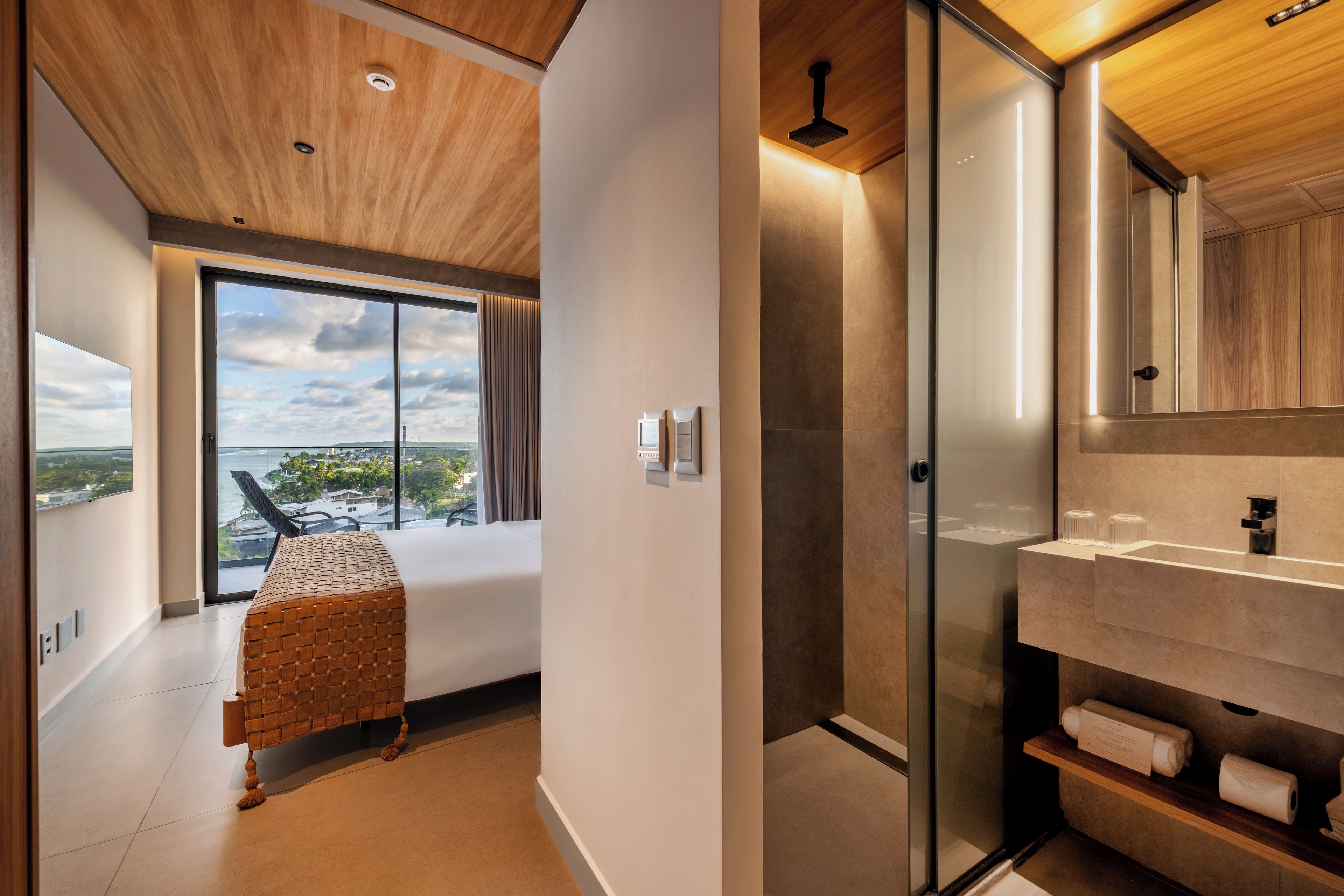 Un baño moderno con cabina de ducha de vidrio, un espejo grande y vistas de la ciudad a través de la ventana.