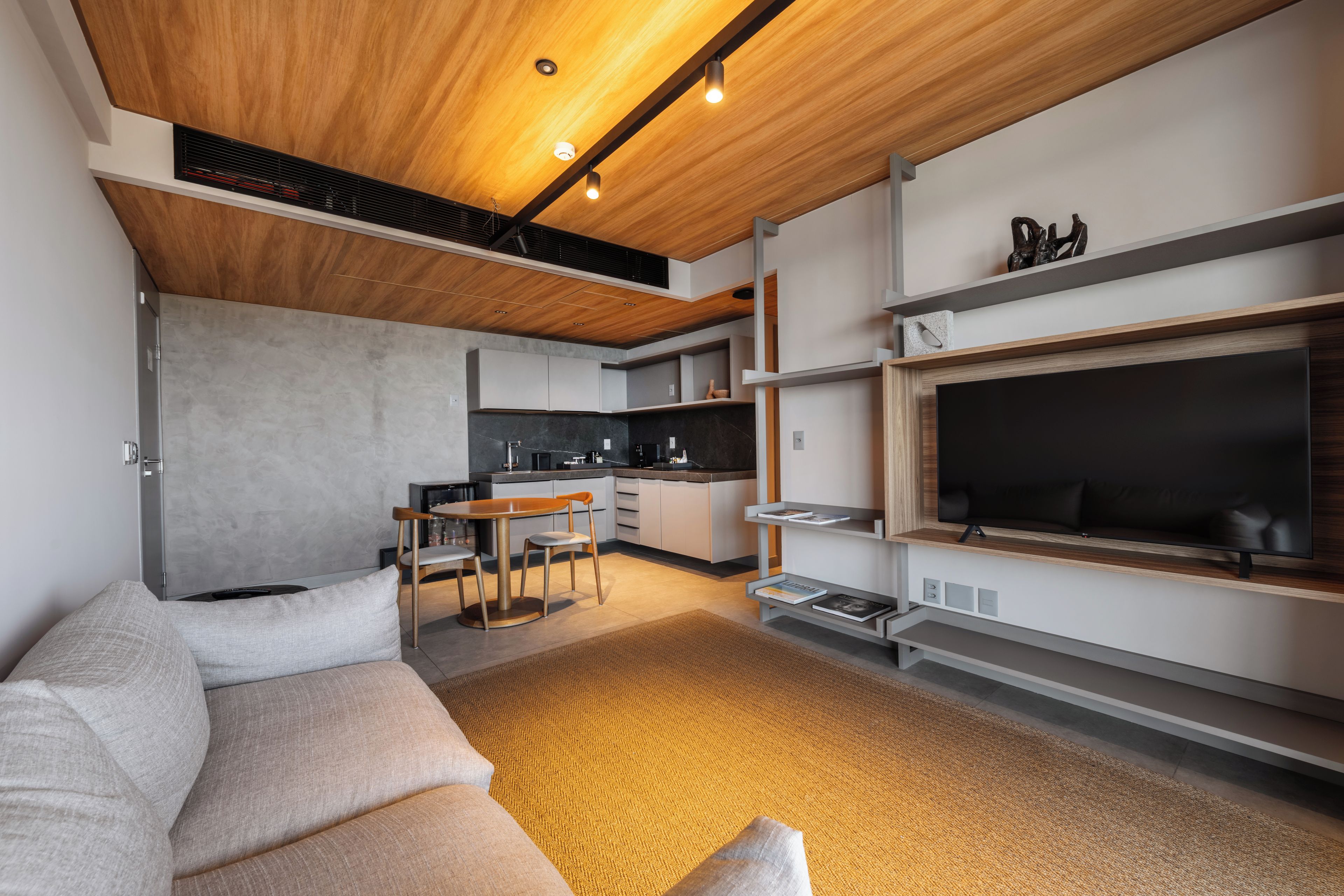 A modern living room with a sofa, a dining area, a kitchen, and a TV.