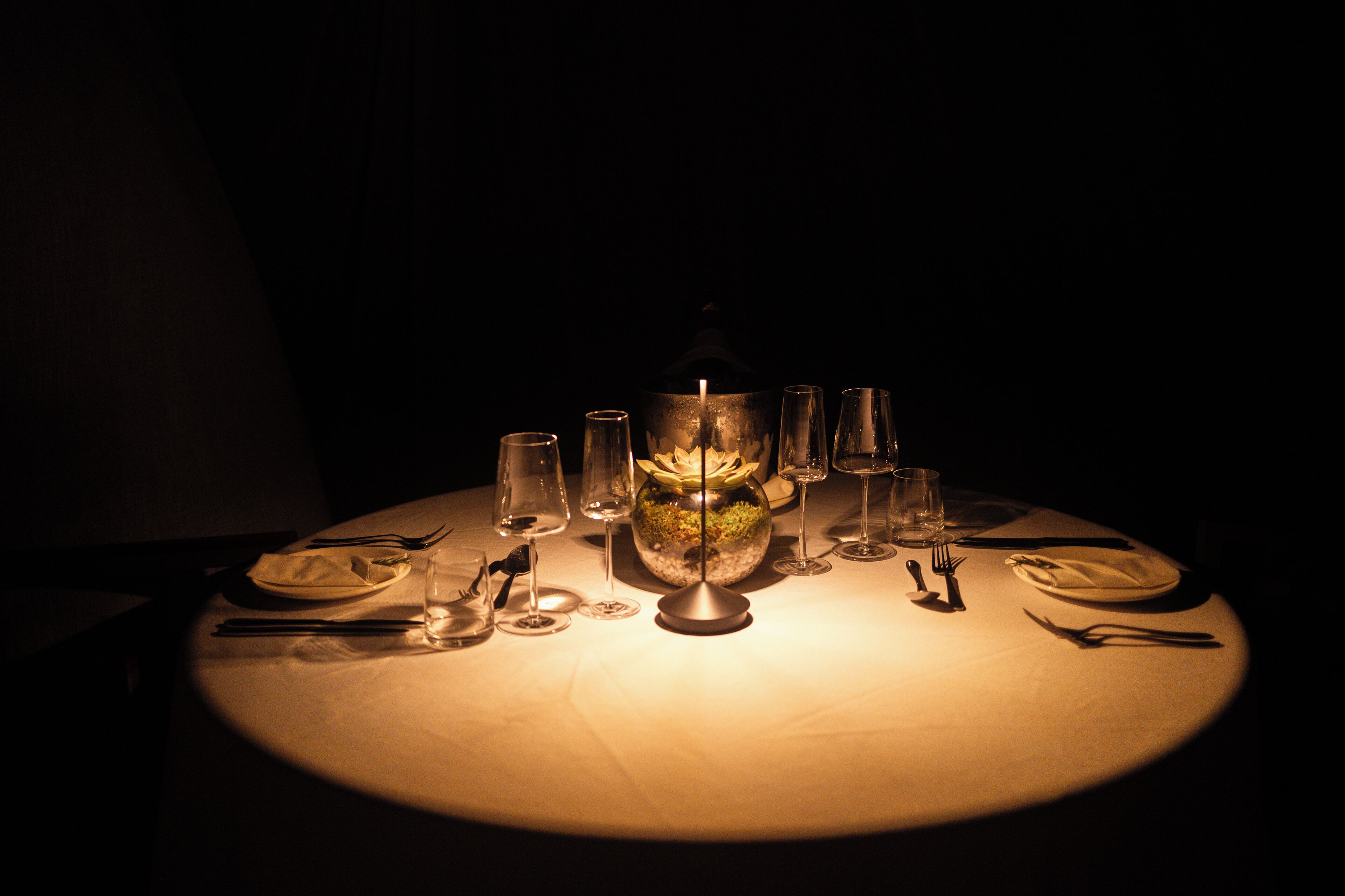 Una mesa lista para cenar con un centro de mesa de velas, copas y cubiertos.