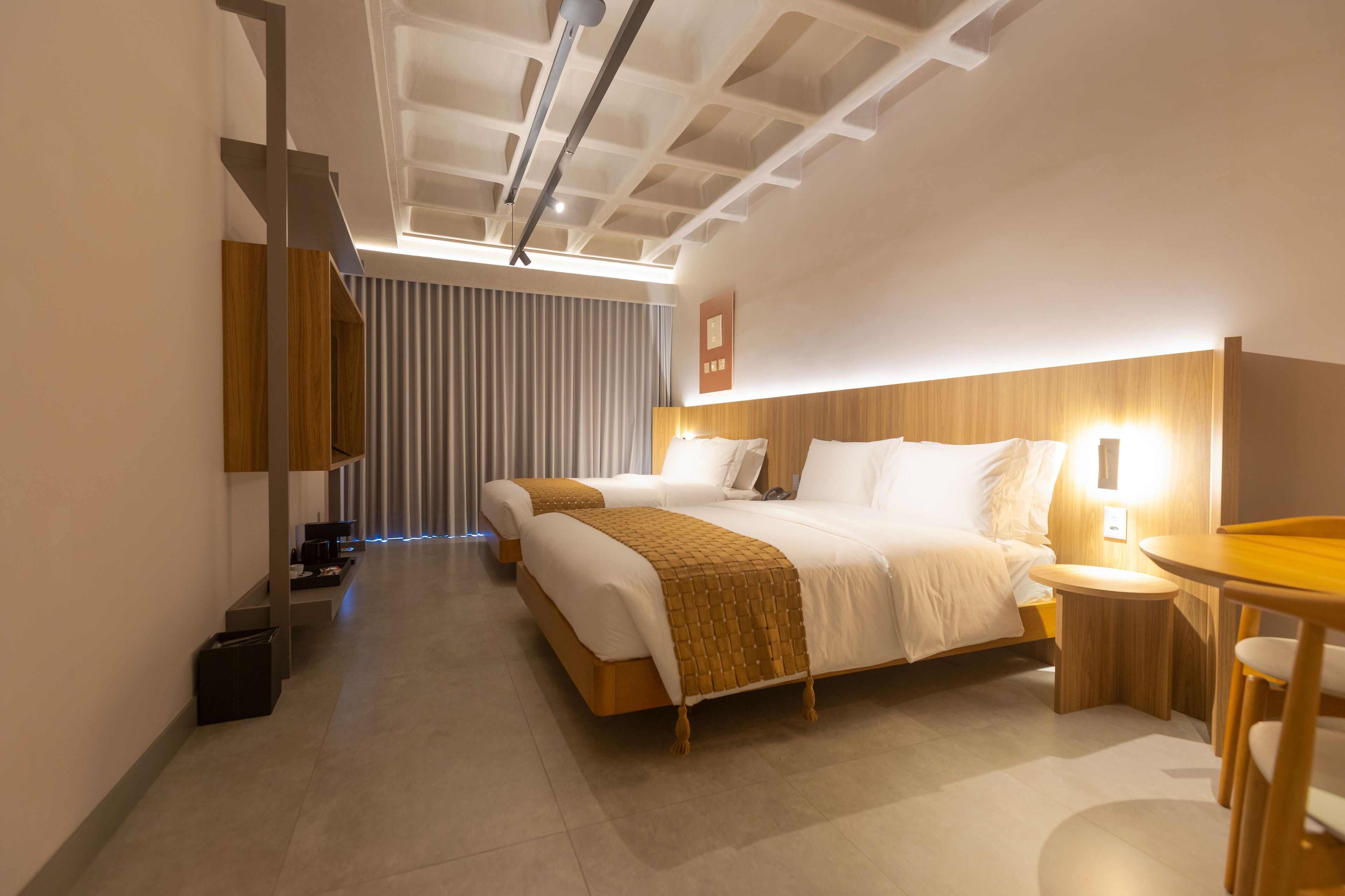 A modern hotel room with a large bed, bedside tables, a desk, and a chair.
