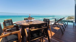 A wooden deck with a round table and chairs, overlooking a clear blue ocean. - Ritz Barra de São Miguel (Barra de São Miguel)