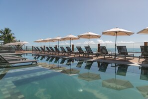 Una piscina al aire libre, sombrillas, tumbonas