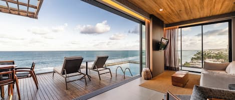 Ein modernes Interieur mit Holzbalkendecke, einem großen Fenster mit Meerblick und einer Sitzecke.