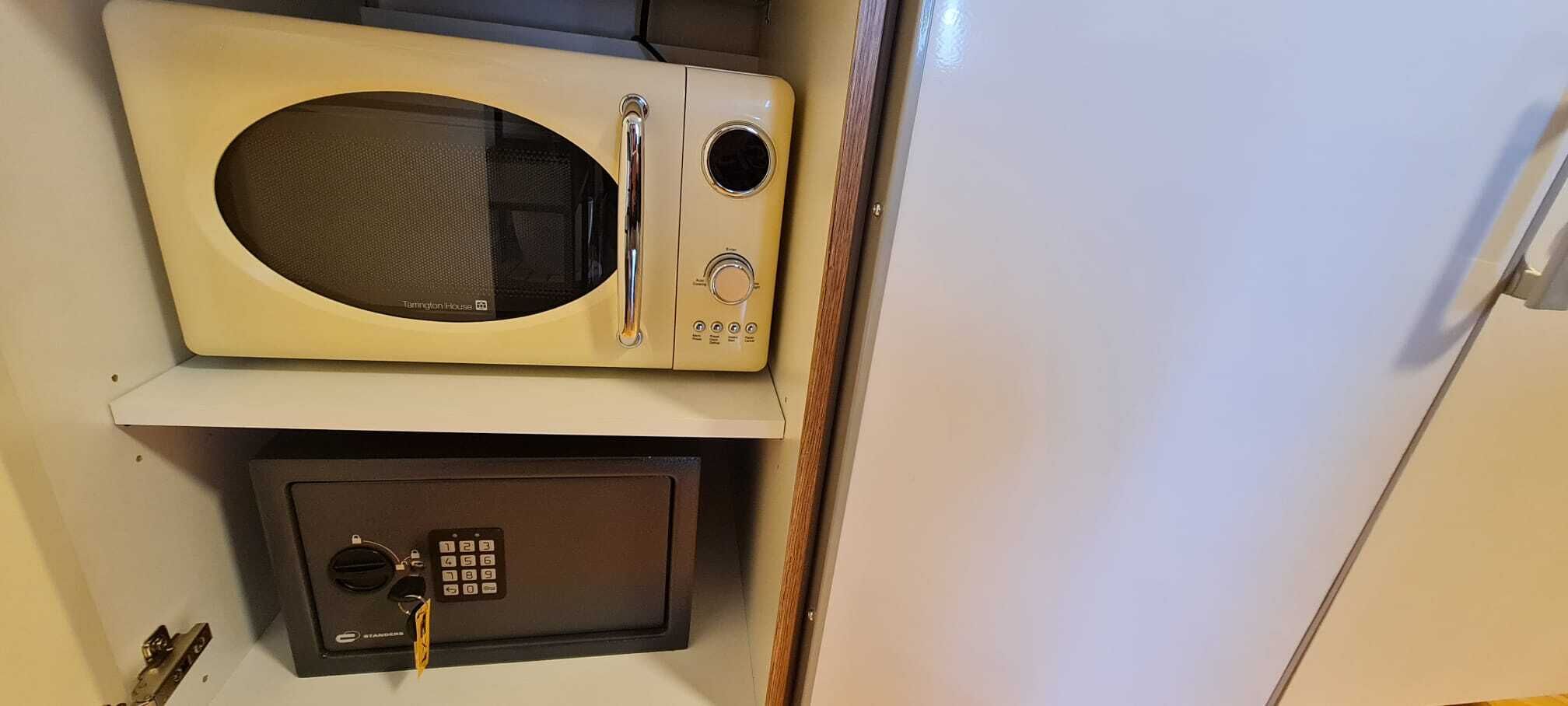 Un microondas y una caja fuerte en un espacio pequeño.