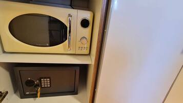 Un microondas y una caja fuerte en un espacio pequeño.