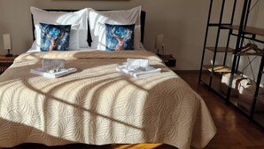 Un llit ben arropat amb un edredó estampat, dos coixins amb disseny de cérvol i una taula de nit amb una làmpada i un petit safata d'articles de tocador.