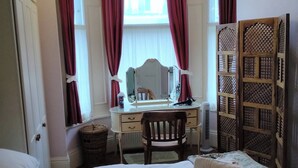 Ein Schlafzimmer mit einem großen Bett, einem Schreibtisch inklusive Spiegel und einem Kleiderschrank.