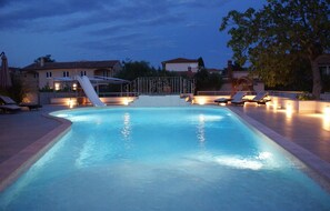 Relax by the pool with a gentle slope leading to a small slide and lounge chairs for unwinding.