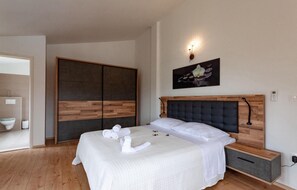 Relax in a serene space with a large bed, wooden wardrobe, and elegant artwork.