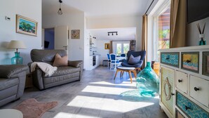 A spacious living room with a sofa, armchairs, and a dining area.