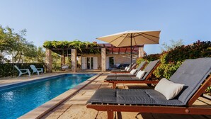 A poolside area with lounge chairs, a pergola, and a covered seating area.