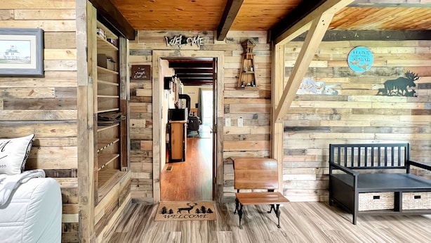Un intérieur en bois avec un banc en bois, un paillasson et une enseigne murale.