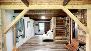 Un intérieur en bois avec un canapé blanc, des bancs en bois et un escalier.