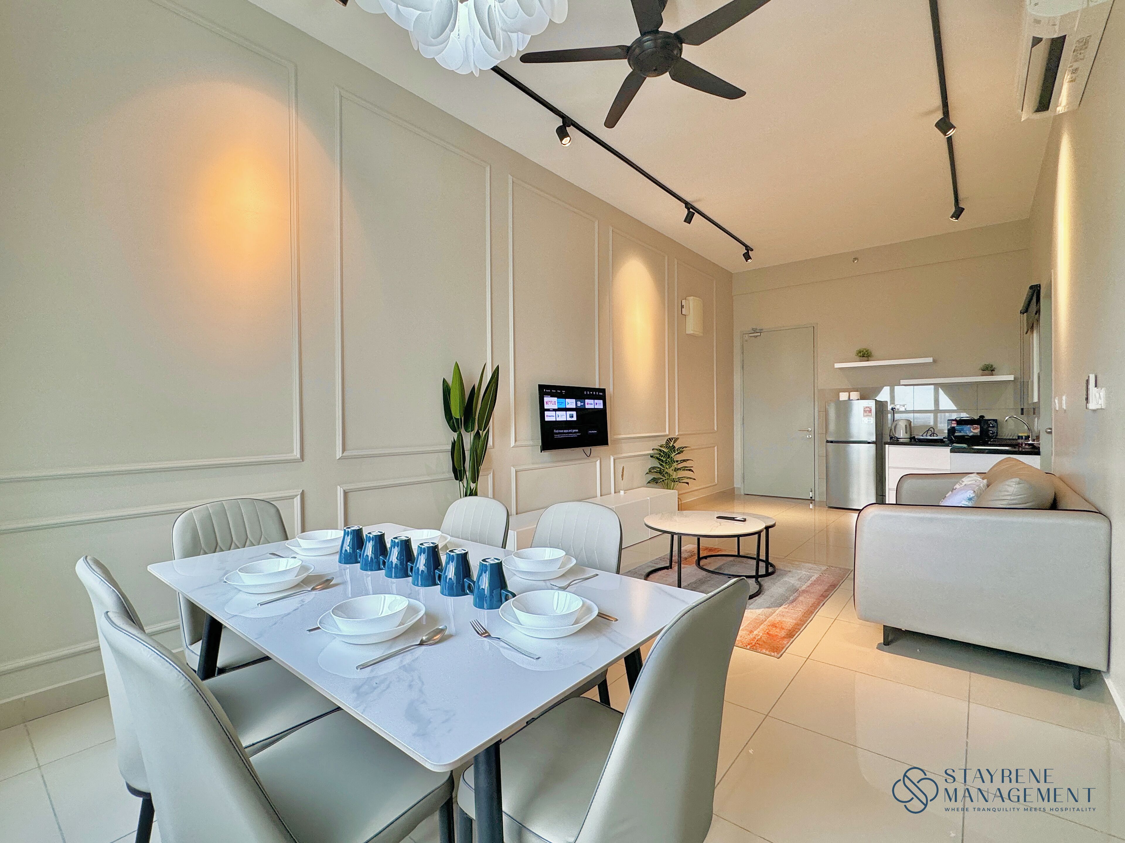 Una sala moderna con comedor, un sofá, un televisor y una cocina al fondo.