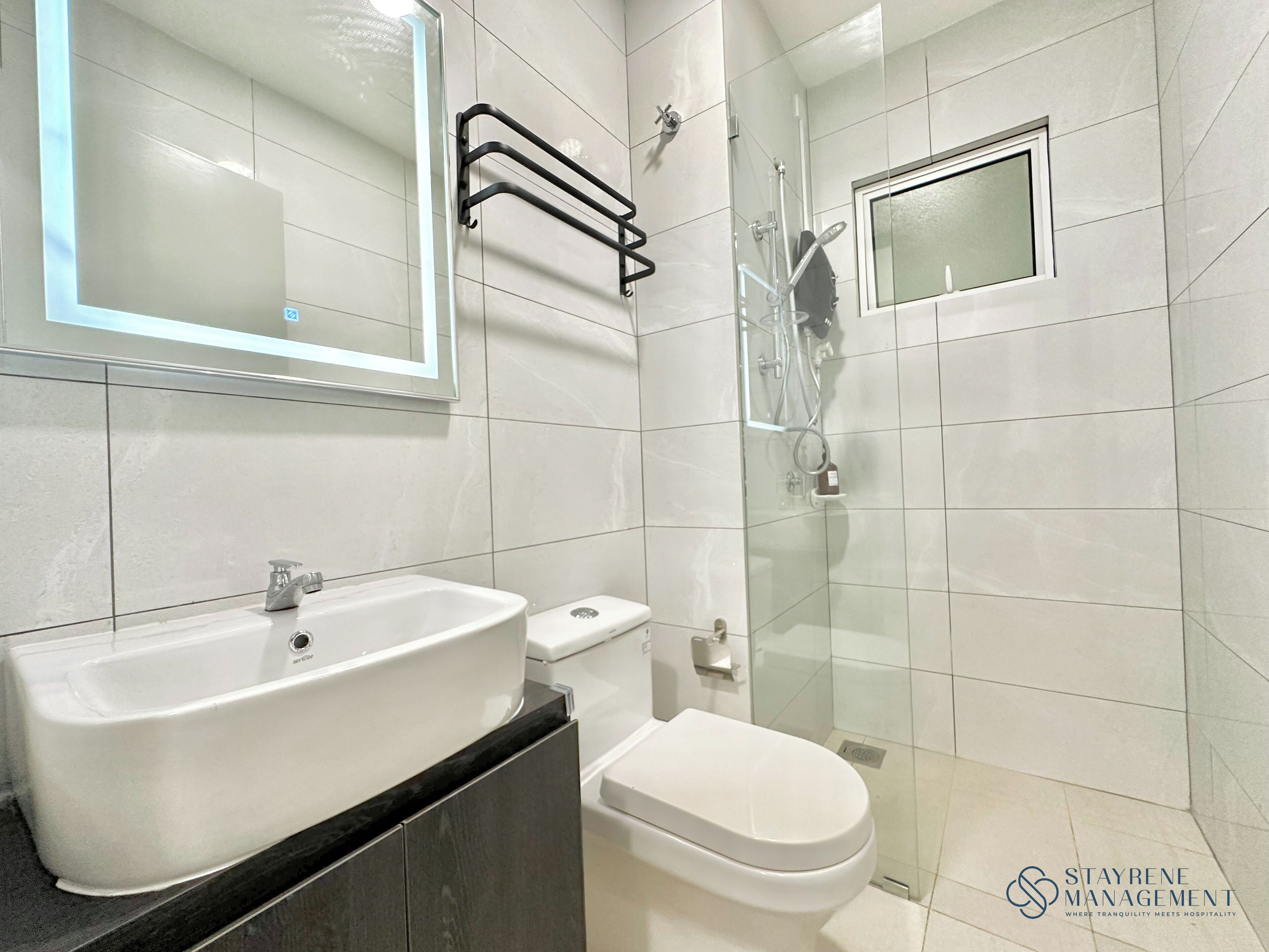A modern bathroom with a white sink, toilet, and glass-enclosed shower.