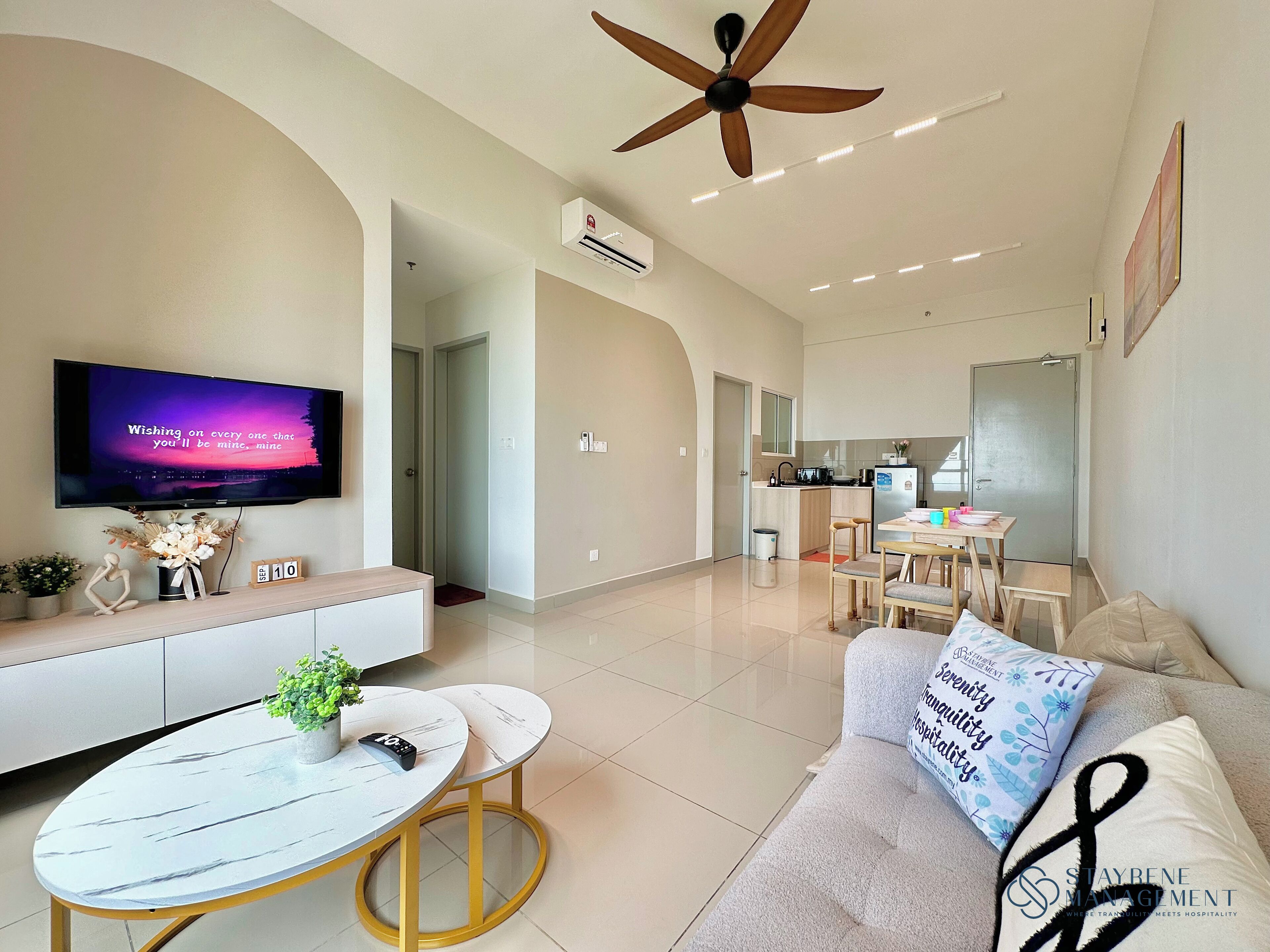 A modern living room with a TV, sofa, and a dining area with a table and chairs.
