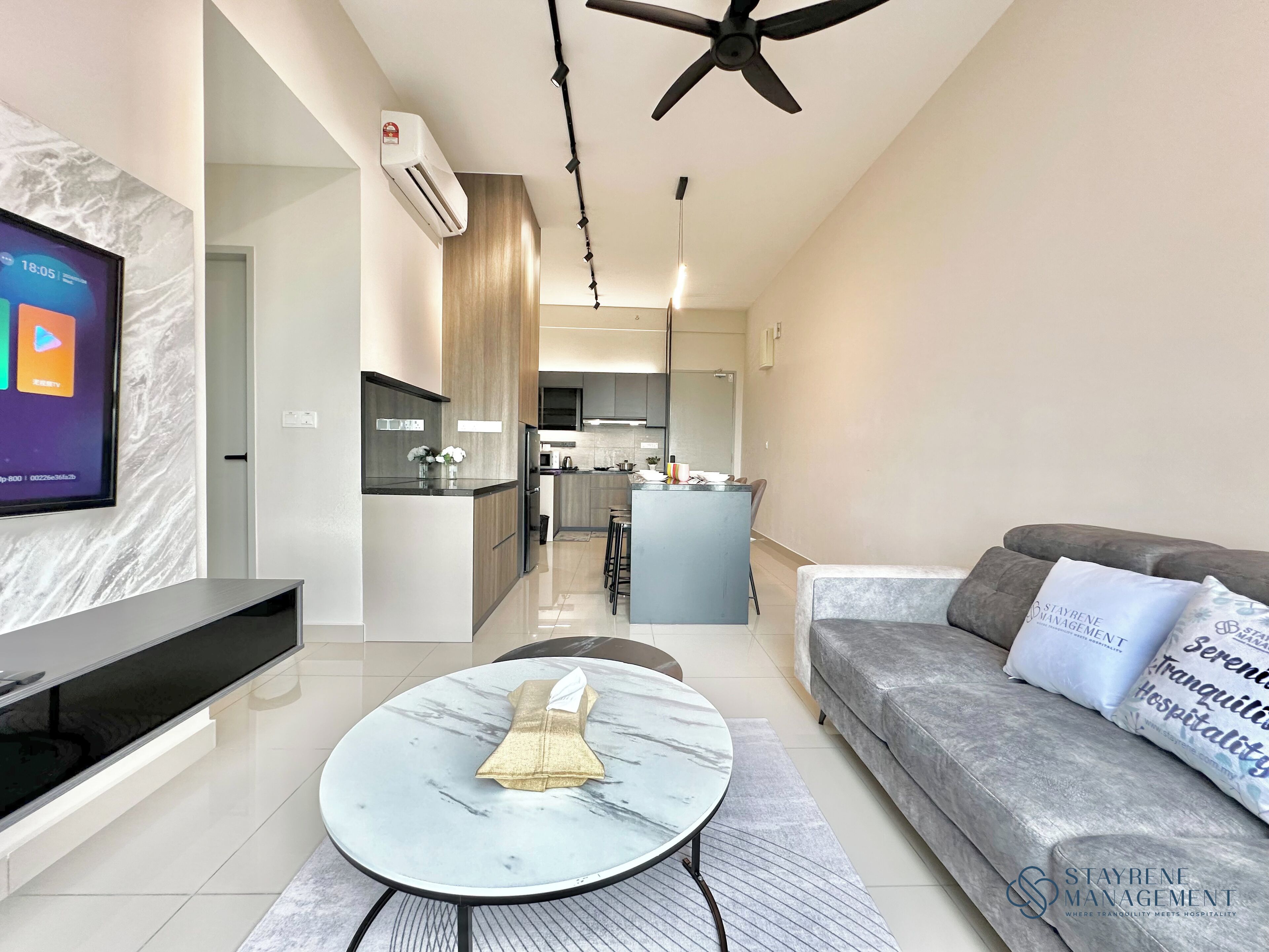 A modern living room with a TV, a marble coffee table, a sofa with cushions, and a ceiling fan.