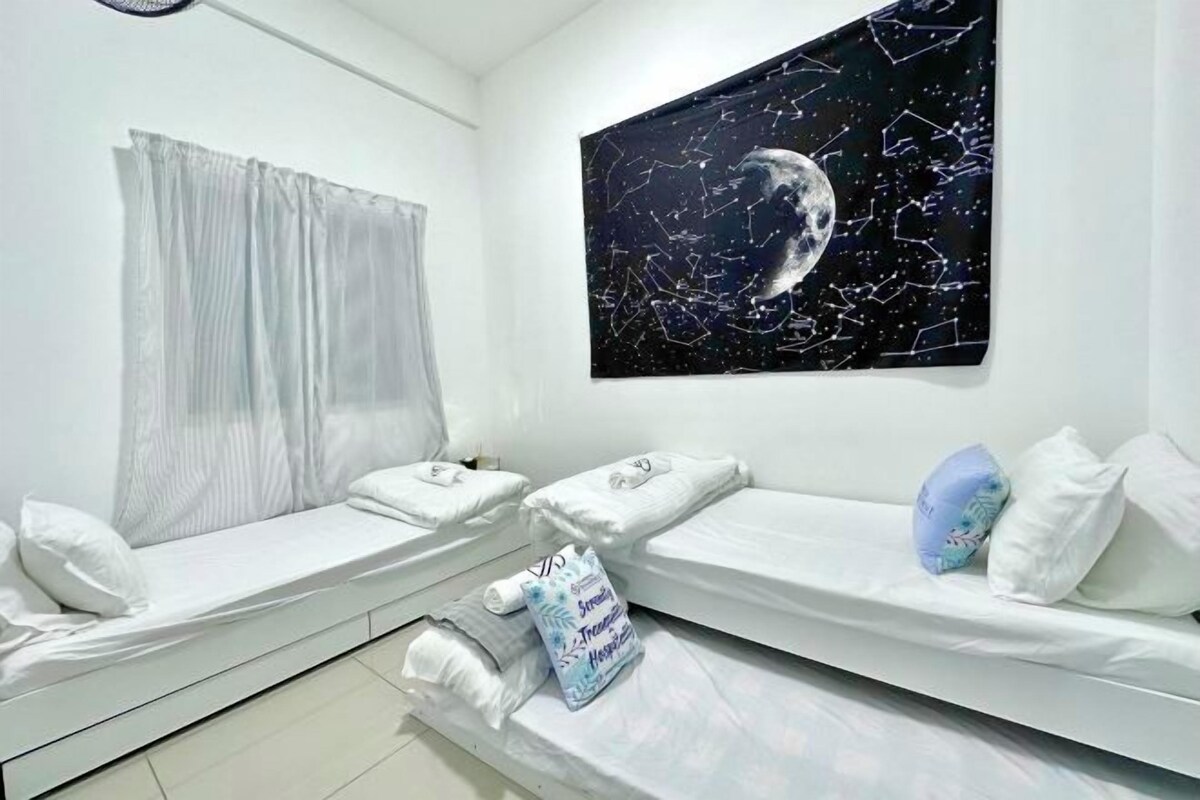 A hotel room with two single beds, a large window with white curtains, and a wall-mounted painting of a moon with stars.