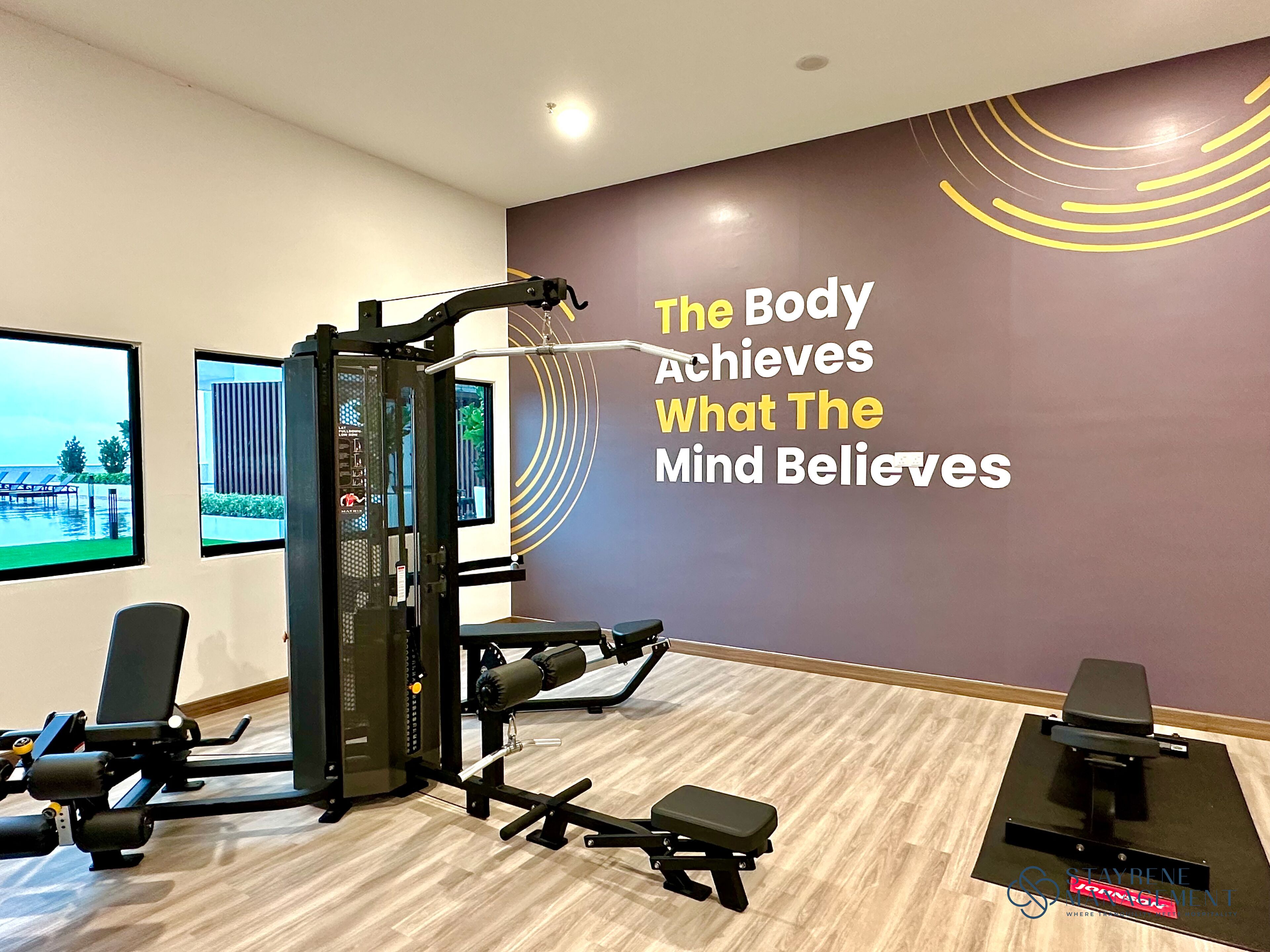A gym with exercise equipment, a motivational quote on the wall, and a view of the outdoors.