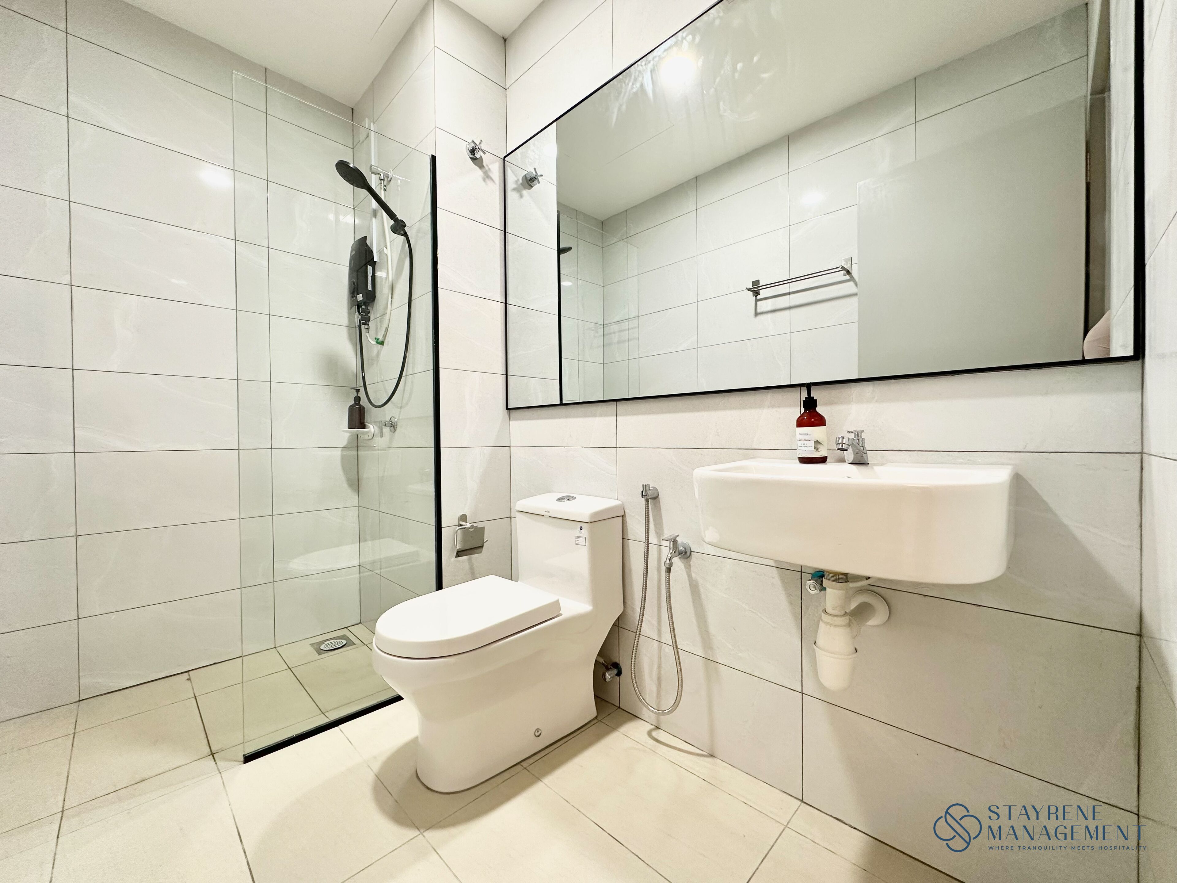 A modern bathroom with a glass-enclosed shower, a white toilet, and a sink with a mirror above it.