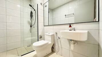 A modern bathroom with a glass-enclosed shower, a white toilet, and a sink with a mirror above it.